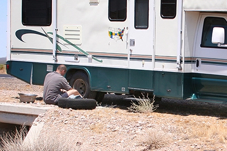 A mechanic performing routine maintenance on RV tires, emphasizing tire care.